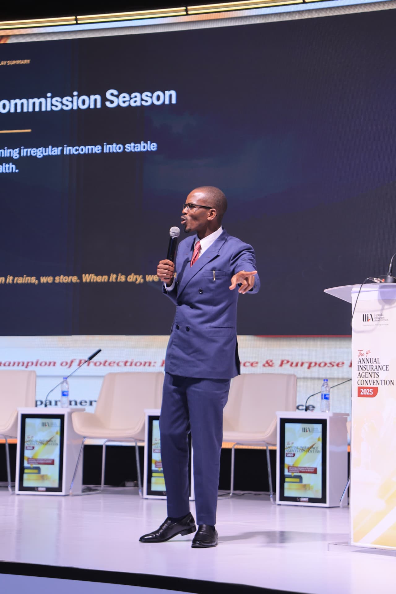 Newton Buteraba mid-keynote in front of a large presentation screen