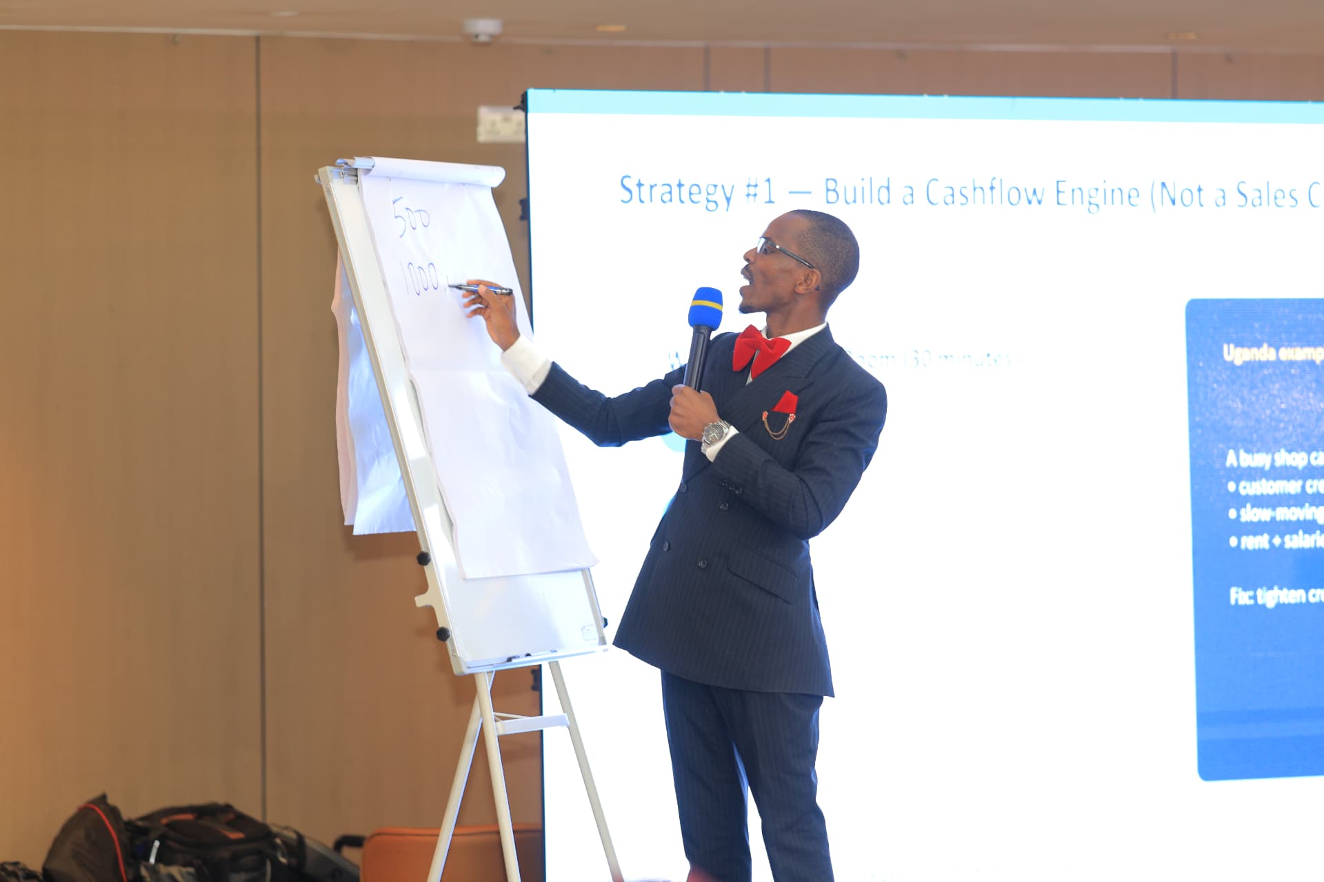 Newton Buteraba writing figures on a flip chart during a masterclass