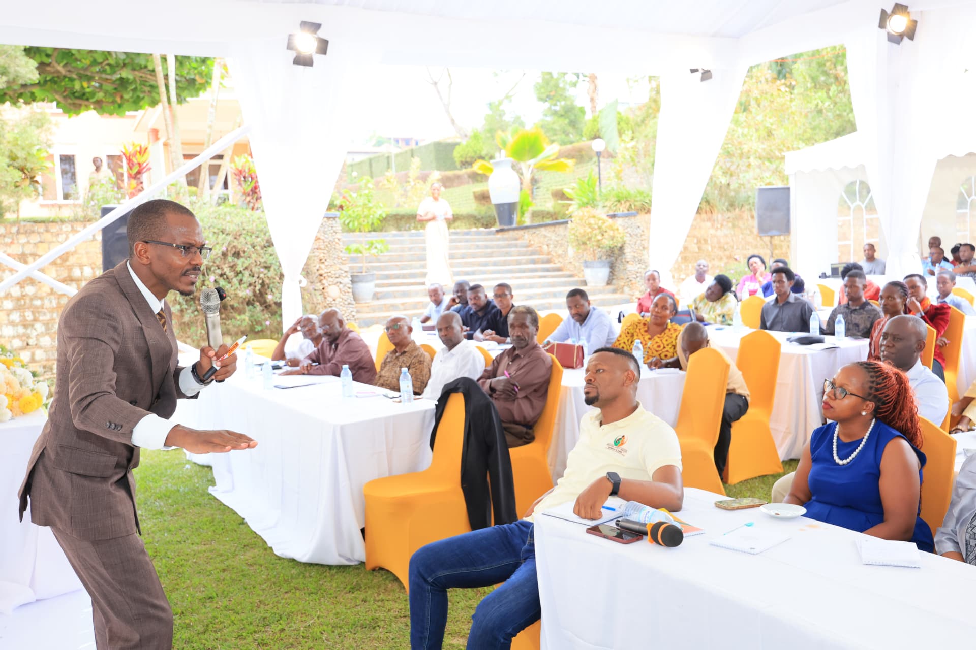 Newton Buteraba speaking to a seated audience under a garden marquee