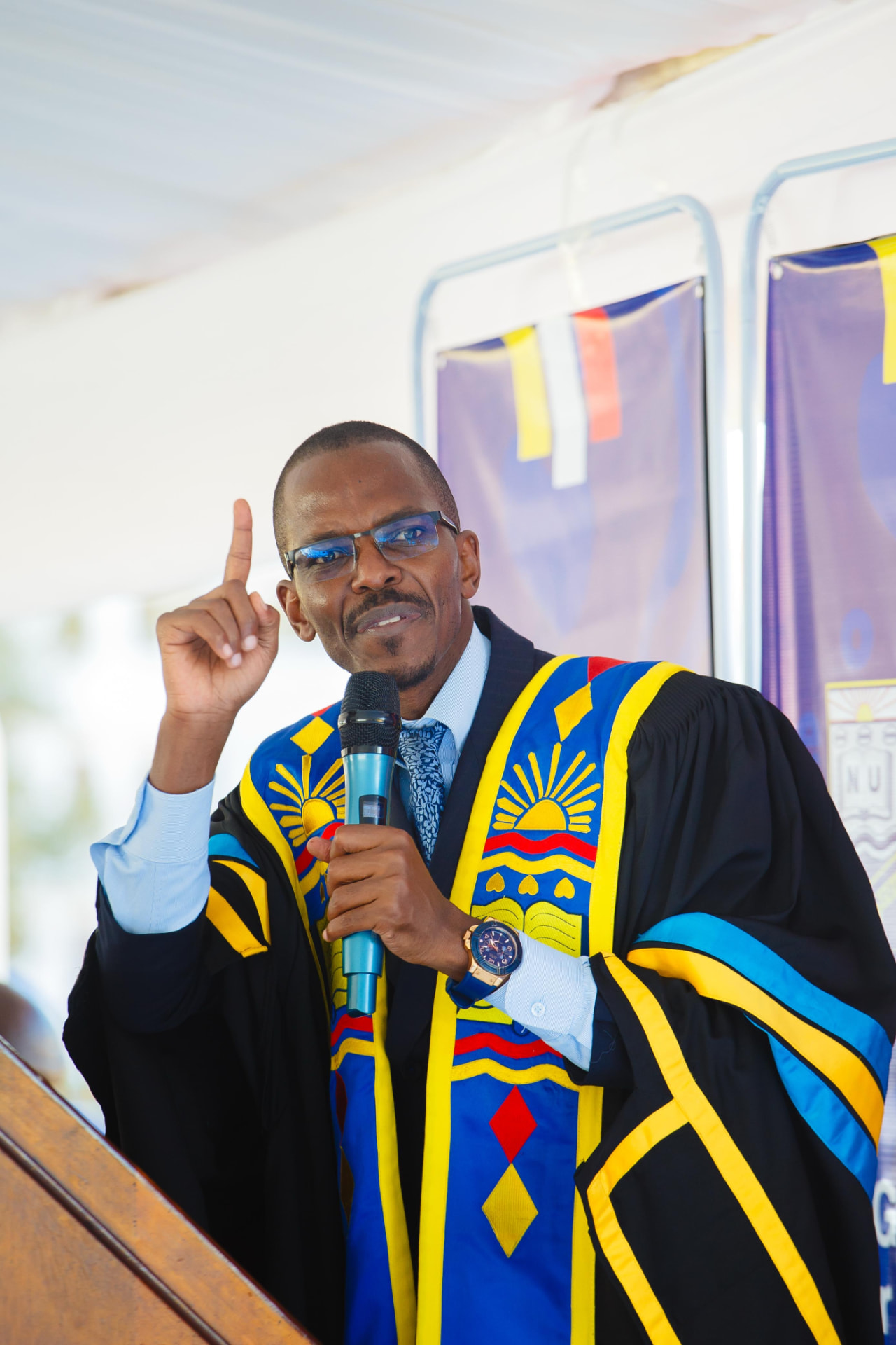 Newton Buteraba addressing a graduation audience with a microphone